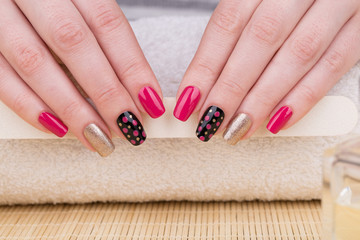 Manicure - Beauty treatment photo of nice manicured woman fingernails. Very nice feminine nail art with nice pink, gold and black nail polish.
