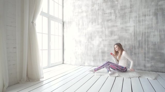 Happy teen girl listening to the music and chatting by smart phone