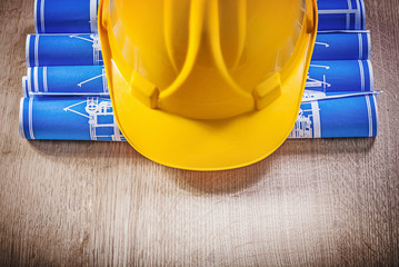 Wooden board with blue rolled up construction plans hard hat
