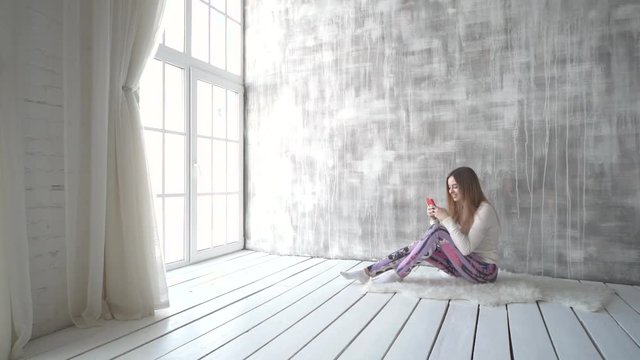 Happy teen girl listening to the music and chatting by smart phone