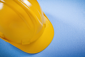 Yellow hard hat on blue surface construction concept