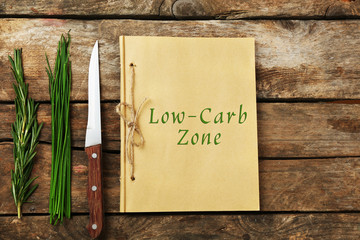 Text Low-Carb Zone in recipe book on wooden background