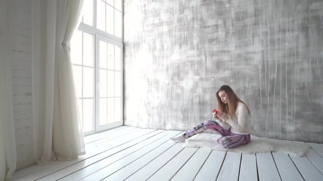 Happy teen girl listening to the music and chatting by smart phone