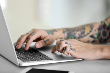 Young man with tattoo using laptop at the table