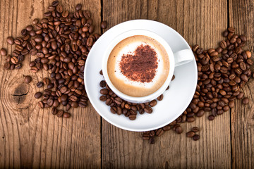 Coffee cup Cappuccino on old wooden table. Heart shape foam, top view.