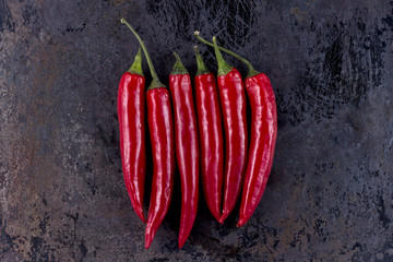 six chili peppers on rusty metal background