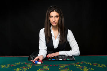 The beautiful girl, dealer, behind a table for poker