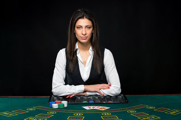 The beautiful girl, dealer, behind a table for poker