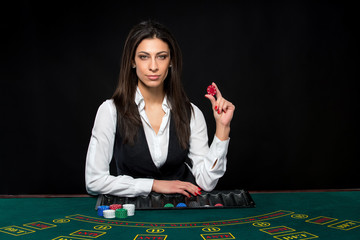 The beautiful girl, dealer, behind a table for poker