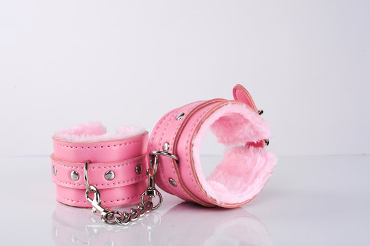 pink sexy handcuffs connected with chain on white screen isolated