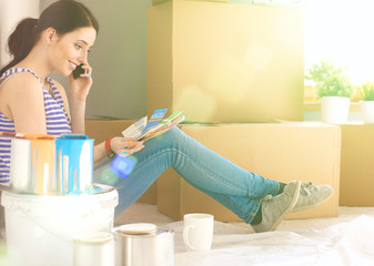 Woman choosing paint colour from swatch for new home sitting on wooden floor