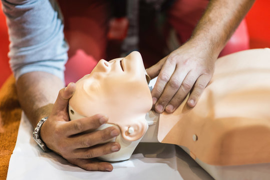 CPR training. Paramedic tilting dummy doll head backwards, checking airways