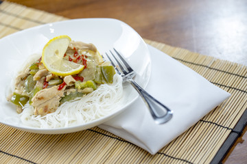 Closeup view of a bowl of thai green curry and rice vermicelli n