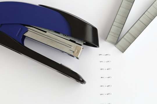 Blue stapler with staples and paper on the table, selective focu