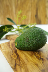 Fresh green avocados with leaves on olive wood