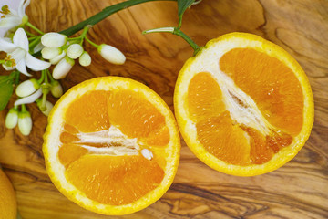 Fresh oranges with leaves and orange tree flowers on olive wood