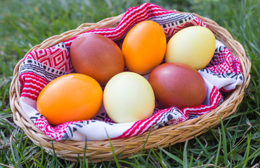 Unique hand painted Easter eggs in basket on grass. Traditional decoration in sun light