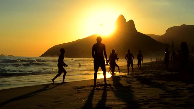 Silhouettes of Carioca Brazilians playing altinho keepy uppy beach football at sunset on Ipanema Beach Rio de Janeiro Brazil