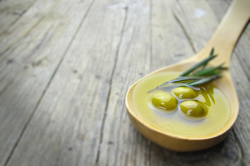 Green olives on wooden spoon