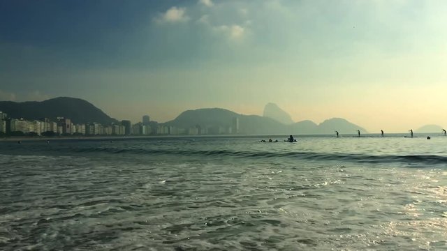 Athletic man running in slow motion through the waves on Copacabana Beach in Rio de Janeiro, Brazil