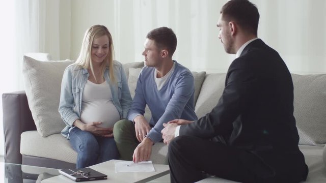 Happy Family Signing Contract with Real-estate Agent. Woman is Pregnant. Shot on RED Cinema Camera.