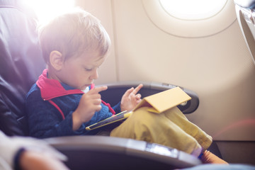 Little boy using tablet on board of aircraft