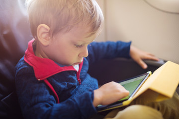 Little boy using tablet on board of aircraft
