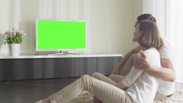 Couple Watching TV with Green Screen. Great for mockup usage. Shot on RED Cinema Camera.