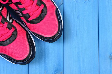Pair of pink sport shoes on blue boards, copy space for text