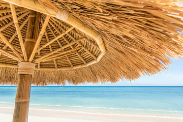 Fototapeta na wymiar Straw umbrella on a beautiful tropical beach
