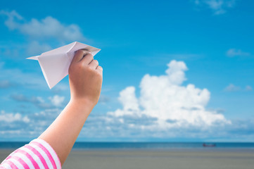 plane paper in children hand over seaand blue sky