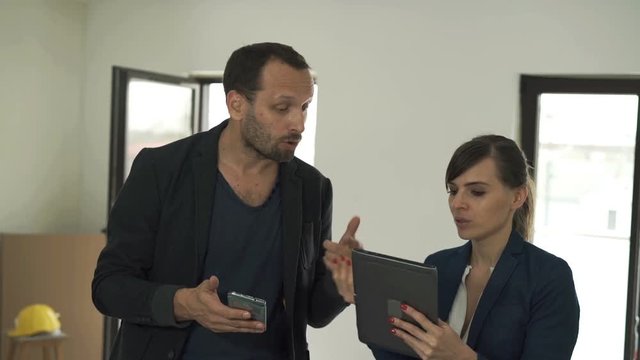 Young couple with smartphone and tablet fighting about new home project
