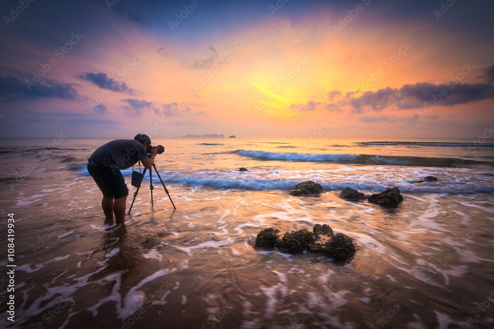 Wall mural silhouette of a photographer with dramatic waves at sunrise