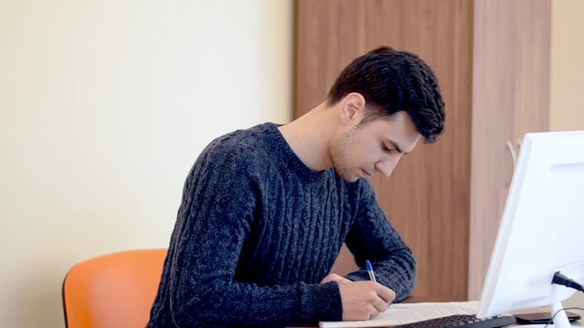 Man is writting down the notes at the office