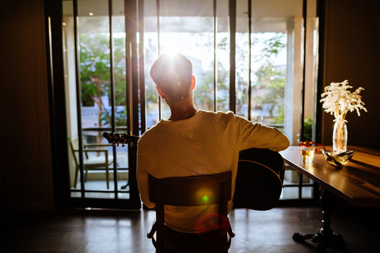 asian artist man play guitar in cafe sunlight