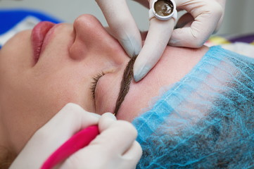 Cosmetologist applying permanent make up (tattoo) on eyebrows.