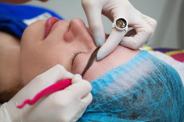 Cosmetologist applying permanent make up (tattoo) on eyebrows.