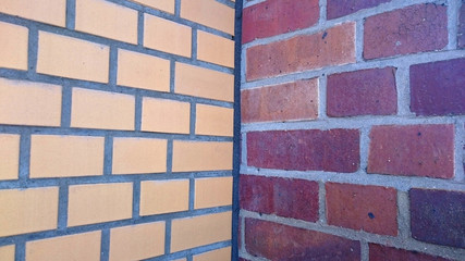 two adjacent brick walls with different patterns and colors meeting in the corner