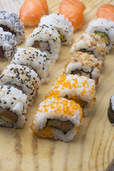 Different Sushi rolls,wasabi and ginger on a plate on wooden bac