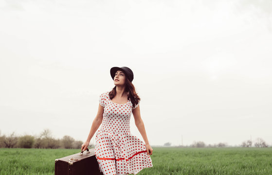 woman in vintage clothes with suitcase in field. Vintage toning