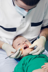 Male dentist examining boys teeth