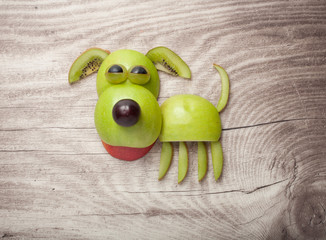 Dog made of apple, kiwi and grape on wood backround