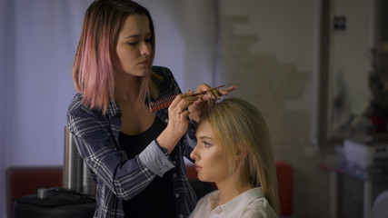 Stylish master hairstyle with pink hair. hairstyle for the attractive blonde in a beauty salon.