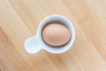 Top view of boiled egg served in egg cup on wooden table.