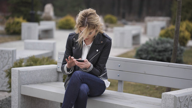 Happy Girl Using A Smart Phone In A City Park Sitting On A Bench