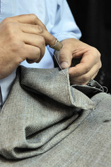 Tailor's hands sewing on businessman clothes