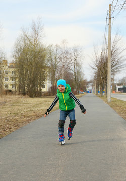 European boy riding on roller skates in the early spring