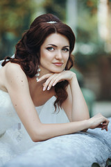 Beautiful brunette bride posing near rustic fountain closeup