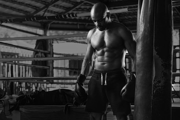 Fototapeta na wymiar Shirtless Muscular Boxer With Punching Bag In Gym