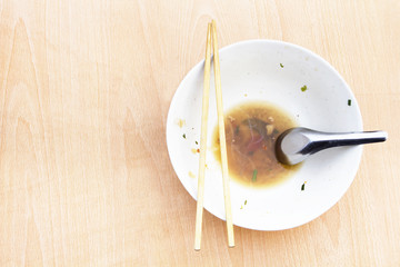 Empty bowl of noodles on wooden table.